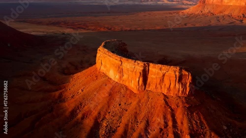 Dramatic Orange Sunlight Illuminates Curved Red Rock Formation in Arid Desert Landscape at Sunset