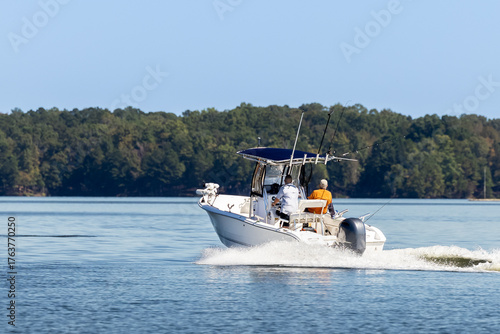 Fishermen on center console fishing boat enjoy summer day on the lake. Power boat cruising on freshwater lake.