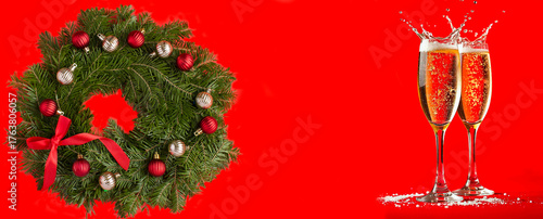 Christmas wreath and two wineglass with champagne on a red background. Copy space