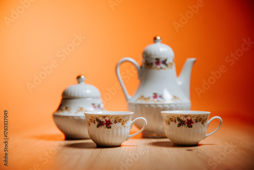 Vintage Porcelain Tea Set with Floral Pattern on Orange Background