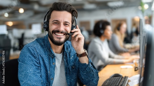 Joyful white male tech support agent chats warmly with a customer using a hands free headset at a call center Grinning service rep advises clients