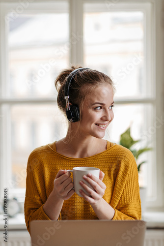 Young female student with headphones sitting at the table and studying.