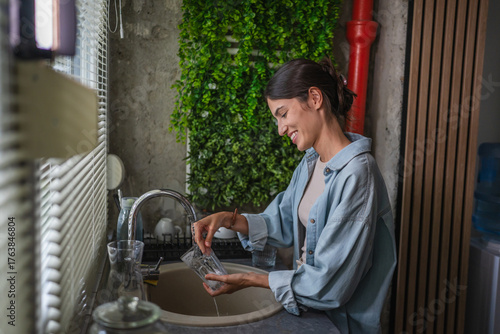 Obraz na plátně Woman washing dishes at kitchen sink, doing housework
