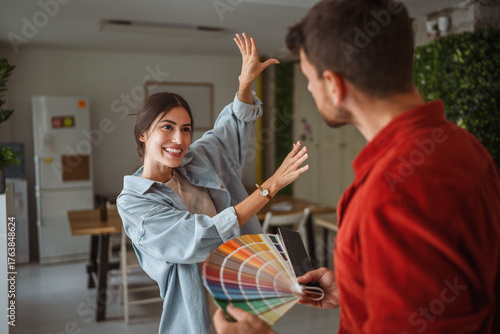 Bild auf Leinwand Woman choosing paint color with interior designer holding color palette