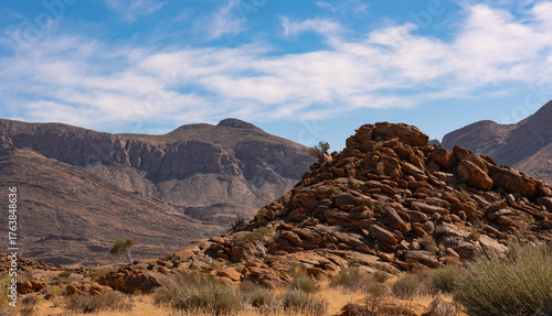 A rocky outcrop against a mountain range and great cloudscape in the Richtersveld in the Northern Cape of South Africa