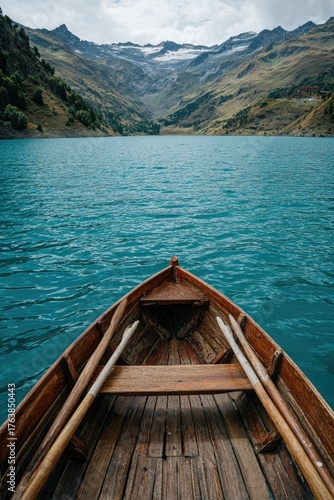 View from a wooden rowboat, azure lake reflecting mountains and overcast sky