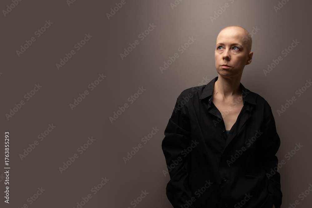 Obraz premium Portrait of a bald woman after cancer treatment wearing a black shirt and looking away, symbolizing emotional depth, reflection, and strength