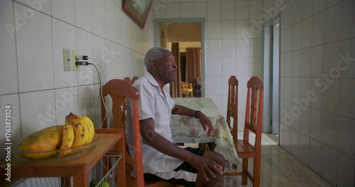 African American Elderly man seated at table with serene expression, radiating calm and introspection, warm and reflective moment captured in everyday life