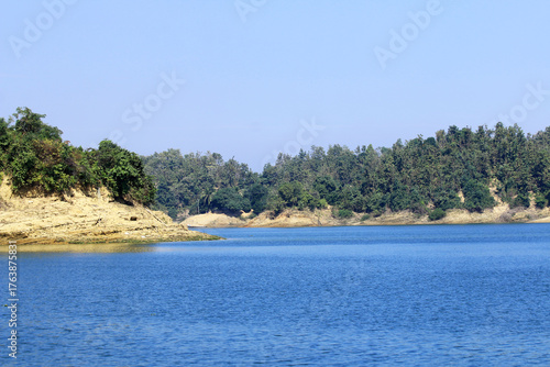 Green Hills and Sparkling Lake under Blue Sky