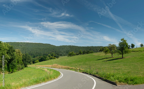 road in the countryside with cirrus clouds in the blue sky
