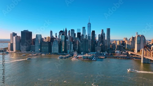 Famous skyline of Manhattan at daytime. Cruise boats move by the waterscape of the East River. Aerial perspective.
