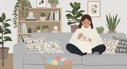 Cozy day at home: Young woman embroidering on the sofa surrounded by plants