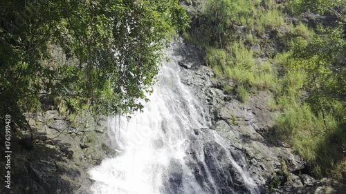 Majestic Waterfall Cascading Down Rocky Cliff Surrounded by Lush Green Vegetation and Trees