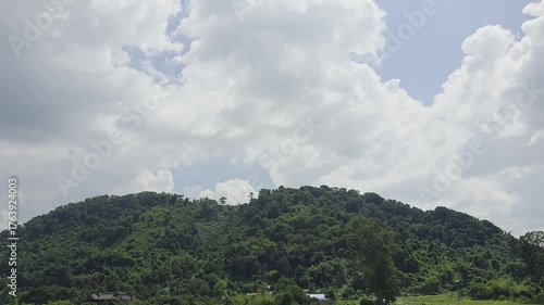 Lush Green Mountain Landscape Under Bright Blue Sky with Fluffy White Clouds