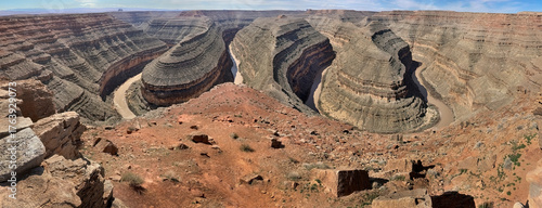 Foto Panoramic view of Goosenecks State Park with meandering San Juan River, red desert cliffs and layered rock formations under bright sky, Utah, USA
