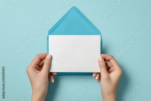 Envelope Held by Hands Against a Light Blue Background, Ready for Sending a L...