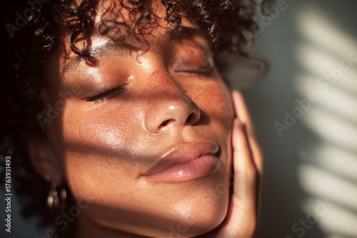 Woman With Curly Hair Enjoys Sunlight While Resting Her Hand on Her Face in a...