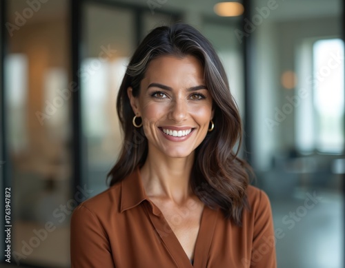 Wallpaper Mural Smiling woman with shoulder-length brown hair in modern office. Soft light highlights features. Wears sleek casual outfit. Background features glass walls, blurred workspace, conveying Torontodigital.ca