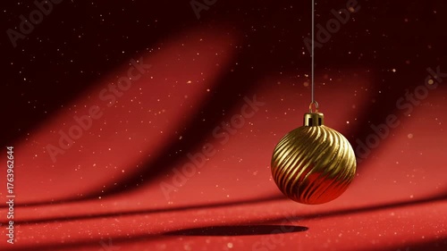 golden christmas ornament hanging against a red glitter background, festive holiday decor