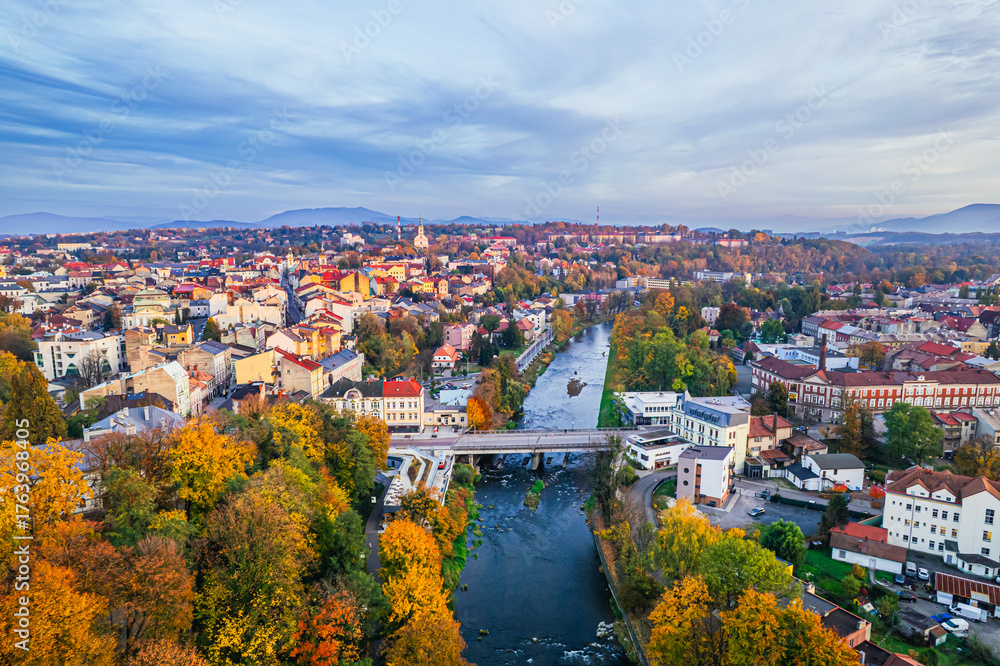 Fototapeta premium Graniczna rzeka Olza w Cieszynie z mostem łączący polski i czeski Cieszyn. Panorama wieczorem.
