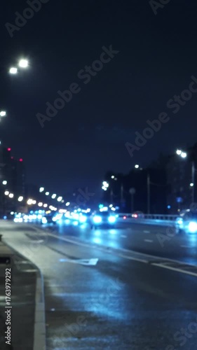 Night city road with car headlights and street lights, urban traffic and modern city atmosphere
