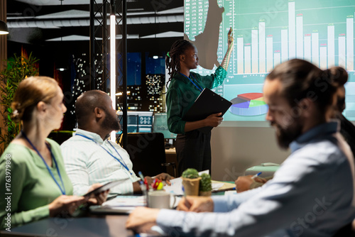Chief financial officer presenting capital funds and revenue data on annual reports in conference room, reviewing profit increase and budget allocation for new project. After hours late meeting.