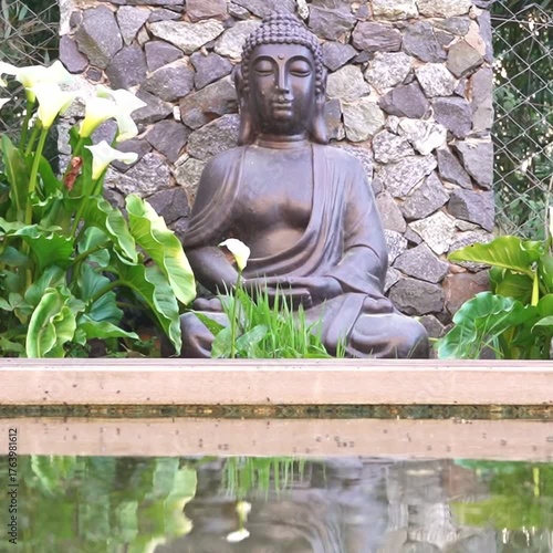 Buddha statue in a peaceful garden reflected in a small water pond