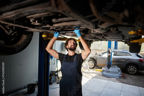 Foto A car mechanic is working underneath a raised car in a garage, focusing on essential repairs and maintenance tasks