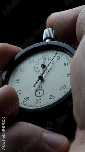 Close-up of male hand activating stopwatch. Idea of performance pressure. Symbol of race against time. Black backdrop emphasizes urgency and concentration in critical moments