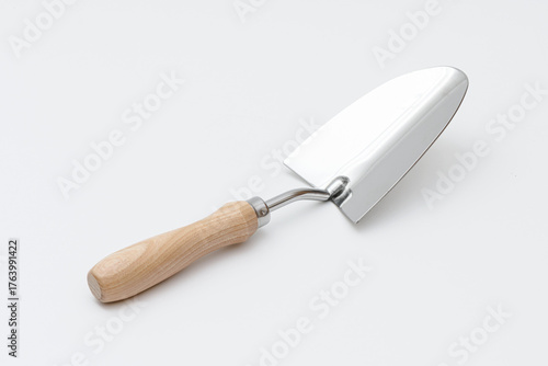 Small garden trowel. A metal trowel with a wooden handle, ideal for digging, planting, and removing weeds, characterized by its sturdy construction and ergonomic design for efficient gardening tasks.
