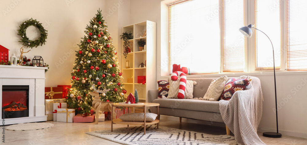Fototapeta premium Beautiful decorated Christmas tree, fireplace and sofa in interior of living room