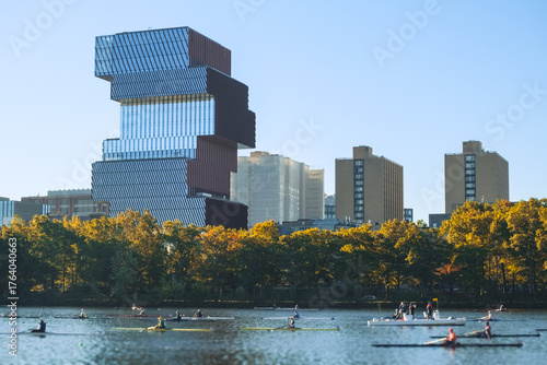 A group of unrecognizable rowers on the Charles River with Boston’s modern skyline and autumn trees in the background.