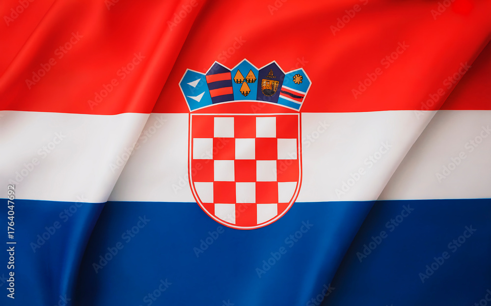 Naklejka premium A photograph of the Croatian flag displayed as a full background, featuring three horizontal stripes in vivid red, white, and blue from top to bottom. The flag's distinctive coat of arms sits prominen