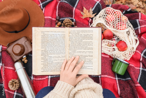 Woman reading book on plaid...
