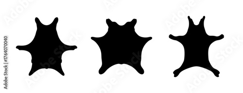 Three black silhouettes of animal skins or pelts displayed as rugs or floor coverings