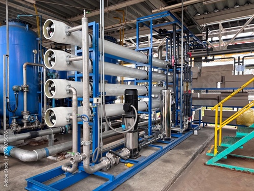 Large industrial Reverse Osmosis (RO) water treatment system with multiple pressure vessels, pipes, and gauges. This complex purification technology is essential for generating high-purity water