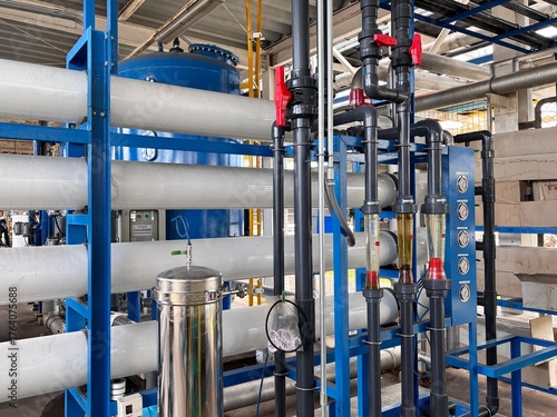 Large industrial Reverse Osmosis (RO) water treatment system with multiple pressure vessels, pipes, and gauges. This complex purification technology is essential for generating high-purity water