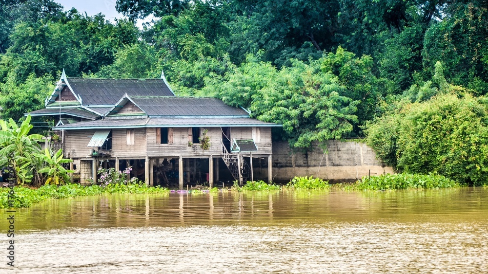 Obraz premium Reflections of Nature: A Serene River House Amidst Lush Green Trees and Stunning Architecture in a Picturesque Landscape