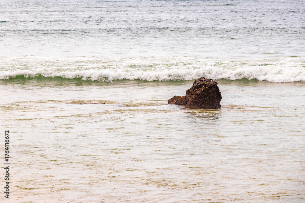 Fototapeta premium Rocky beach with rocks waves turquoise water in Patong Thailand.