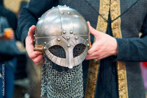 A medieval warrior's helmet shown from the hands. A highly detailed metal helmet with its chainmail and very well maintained. A medieval warrior's helmeted hands.
