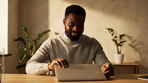 Young Man Working on Laptop in Bright Modern Workspace at Home