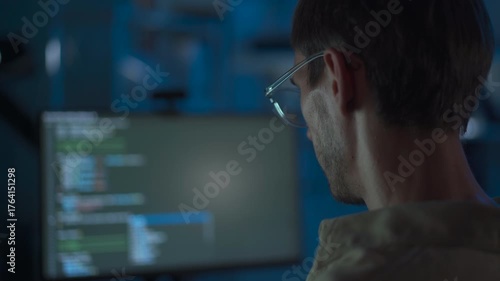 Cybersecurity engineer working late at computer in dark office