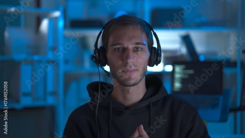 IT support specialist assisting customer via headset in dark office.