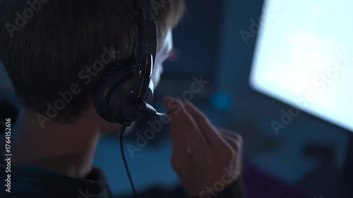 IT support specialist assisting customer via headset in dark office.