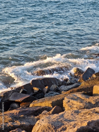 Coastal sunset with waves crashing on rocky shoreline makes for stunning landscape photography, perfect for travel or nature publications