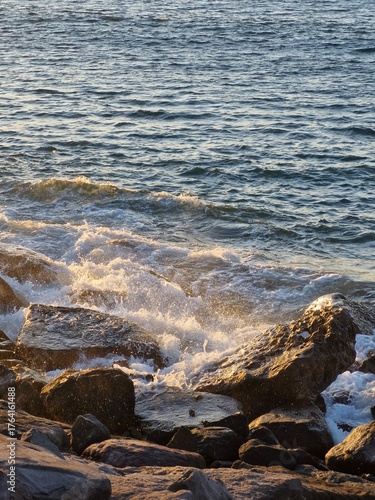 Golden hour waves crash on rugged rocks, creating a stunning coastal scene that evokes peace and tranquility, perfect for travel and nature themes