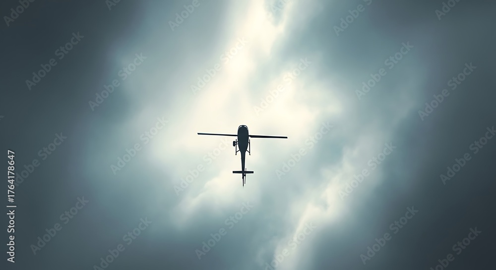 Naklejka premium Silhouette of a military attack helicopter flying upwards into a bright sky with dramatic clouds