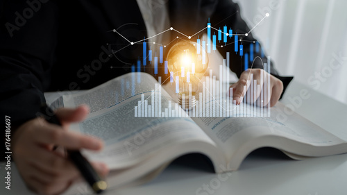 Konstfotografi A business professional engaged in financial analysis using a textbook, complemented by digital charts to enhance understanding and strategic planning