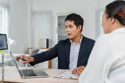 Business man discussing data on a laptop with a female colleague during an office meeting, presenting financial analysis