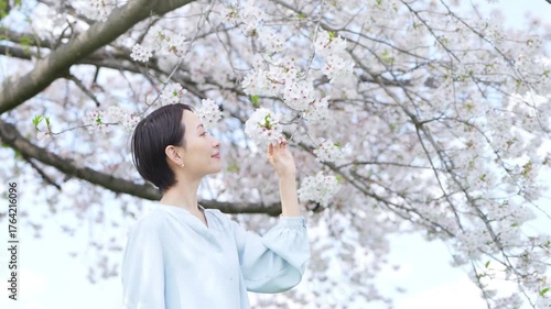 桜の花びらを見る若い女性　ライフスタイルイメージ